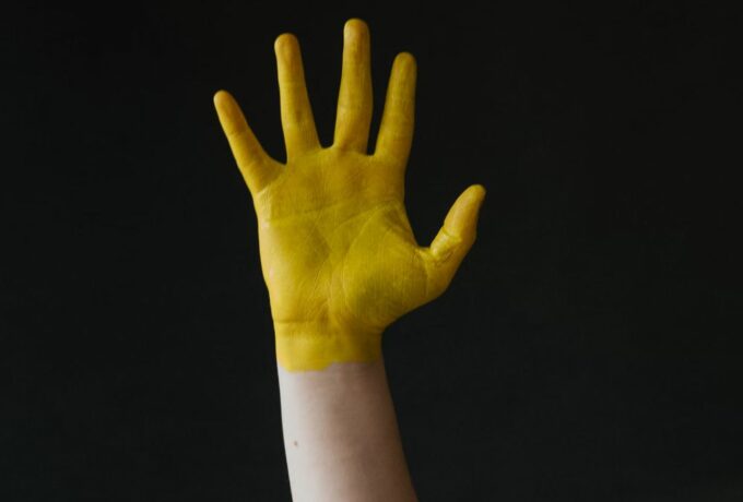 raised-hand-covered-in-yellow-paint