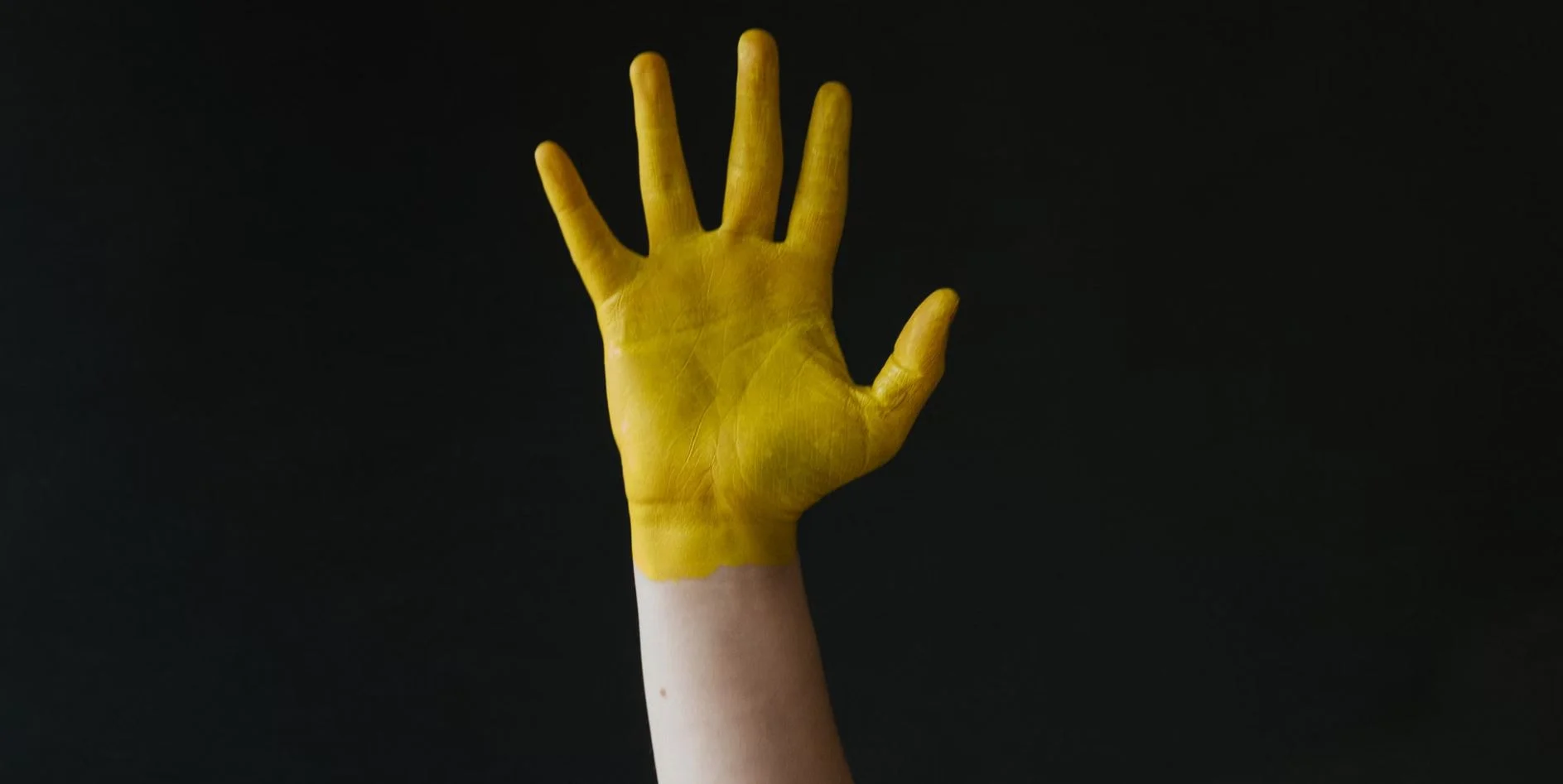raised-hand-covered-in-yellow-paint